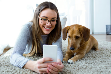 girl looking at smartphone with dog at her side