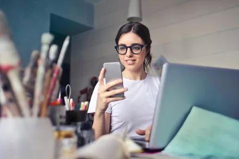 Thanh niên cầm điện thoại khi đang ngồi ở bàn làm việc.