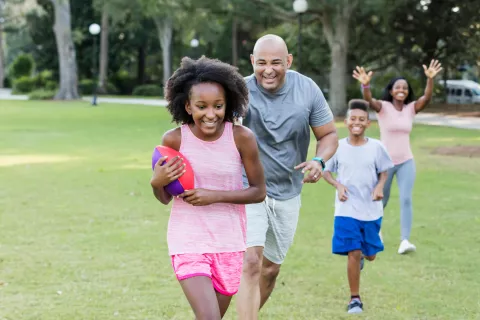 Two adults playing football with two children.
