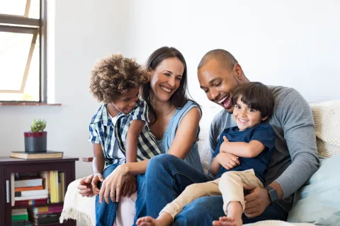 Two adults with two children on their laps while sitting on a couch.