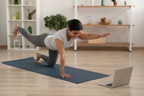 Tus poj niam ua yoga, saib lub laptop.