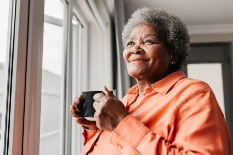 Woman holding a mug, smiling.