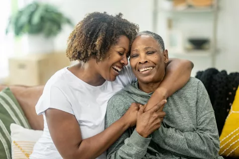 An adult and senior adult embracing each other