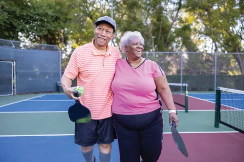 A couple smiles on the pickleball court.