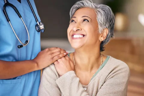 A woman smiles and looks at a medical professional.