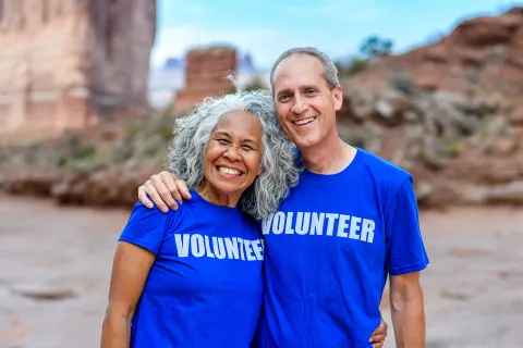 A man and woman smile while wearing t-shirts that read volunteer.
