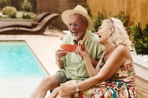 A couple eats by the pool.