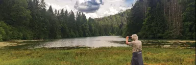 A man snaps a photo of a nature scene.