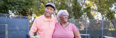 A couple smiles on the pickleball court.