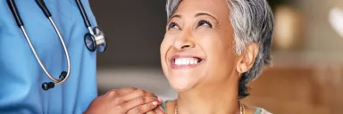 A woman smiles and looks at a medical professional.