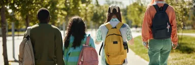 Four students walking side by side outside, facing away from the camera