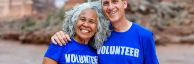A man and woman smile while wearing t-shirts that read volunteer.