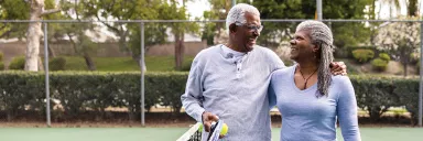 A copule smiles on the tennis court.