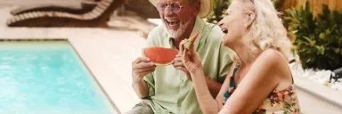 A couple eats by the pool.