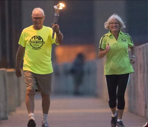 Patsy Lillehei jogging along side the torch for the Senior Games. 